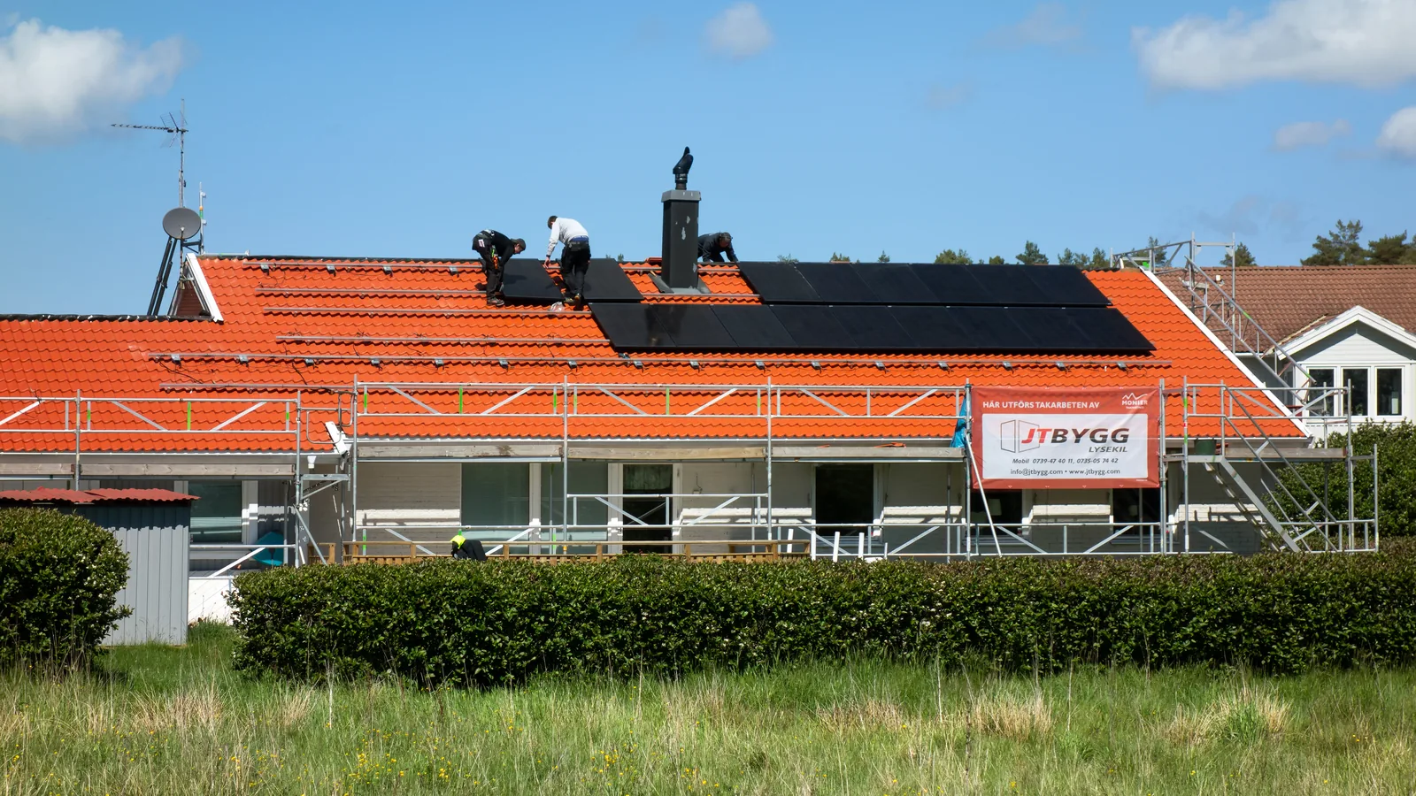 Installers mounting solar panels on a residential rooftop on a clear day